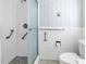 Bright bathroom featuring a walk-in shower with grab bars, seashell wallpaper, and white tiled walls at 1301 62Nd S Ter, St Petersburg, FL 33705