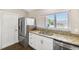 Well-lit kitchen features stainless steel refrigerator, granite counters, and white cabinetry at 13040 Hanley Dr, Spring Hill, FL 34609