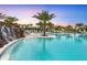 Stunning resort style community pool with palm trees and a rock waterfall feature at sunset at 14727 Eagle Branch Dr, Nokomis, FL 34275