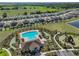 Aerial view of community pool, playground, and clubhouse surrounded by lush landscaping and numerous homes at 16704 Sunburst Lake St, Wimauma, FL 33598