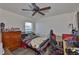 Bedroom setup with wooden dresser, gaming chair, and ceiling fan at 16704 Sunburst Lake St, Wimauma, FL 33598