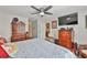 Comfortable main bedroom with a ceiling fan, warm-toned dressers, and a calming blue patterned bedspread at 16704 Sunburst Lake St, Wimauma, FL 33598