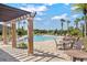 Relaxing community pool area with lounge chairs, tables, and pergola, surrounded by swaying palm trees at 17731 Bright Wheat Dr, Lithia, FL 33547