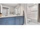 Bathroom featuring double sinks, blue vanity, and a bathtub with white tiles at 18017 Ramble On Way, Land O Lakes, FL 34638