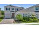 Beautiful two-story home featuring a well-manicured lawn, lush landscaping, and a charming red door at 18017 Ramble On Way, Land O Lakes, FL 34638