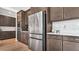 Modern kitchen with stainless steel refrigerator and appliances and dark wood cabinets at 18017 Ramble On Way, Land O Lakes, FL 34638