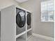 Laundry room features two gray front-load washers and dryers with bright white shelving at 18017 Ramble On Way, Land O Lakes, FL 34638