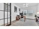 Bright home office featuring modern light fixture, large rug, and view through black framed glass door at 18017 Ramble On Way, Land O Lakes, FL 34638