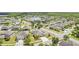 Expansive aerial perspective of a neighborhood showcasing numerous homes, lush greenery, and tranquil ponds at 18677 Milton Keynes Ct, Land O Lakes, FL 34638