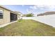 Wide view of fenced backyard featuring a well-maintained lawn and screened patio at 18677 Milton Keynes Ct, Land O Lakes, FL 34638