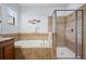 Bathroom featuring soaking tub, shower, and neutral tile surround at 18677 Milton Keynes Ct, Land O Lakes, FL 34638