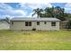 Backyard view of the home, showing the lawn and the back of the home on a sunny day at 1980 Taylor Lake Cir, Largo, FL 33778
