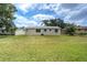 View of the home's backyard with lush green lawn and some palm trees in the background at 1980 Taylor Lake Cir, Largo, FL 33778