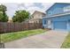 View of the house showing the driveway, garage, and the fenced in yard on a sunny day at 2130 W Spruce St, Tampa, FL 33607