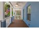 Charming front porch featuring white railings, a ceiling fan, and a textured blue wall at 2130 W Spruce St, Tampa, FL 33607