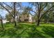 Charming two-story home with lush landscaping, mature trees, and expansive green lawn at 2175 Oak Forest Ln, Palm Harbor, FL 34683