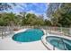 Sparkling pool and whirlpool spa with lounge chairs and a white fence in a lush community at 2175 Oak Forest Ln, Palm Harbor, FL 34683
