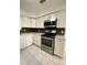Well-lit kitchen boasts stainless steel appliances, white cabinets, and modern backsplash on tiled floors at 2400 13Th S Ave, St Petersburg, FL 33712