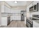 Modern kitchen featuring white cabinets, stainless steel appliances, and gray luxury vinyl flooring at 27330 Coral Springs Dr, Wesley Chapel, FL 33544