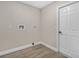 A utility area with neutral paint, wood-look flooring, and a door to the side yard at 27330 Coral Springs Dr, Wesley Chapel, FL 33544