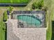 Aerial view of the screened-in pool with spa and patio, surrounded by lush green lawn, trees, and landscaping at 2908 89Th E Ave, Parrish, FL 34219