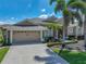Well-maintained home with a two-car garage, lush landscaping, and mature palm trees, set under a sunny sky at 2908 89Th E Ave, Parrish, FL 34219