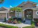 Charming home entrance with a two-car garage, palm trees, and inviting double doors with decorative details at 2908 89Th E Ave, Parrish, FL 34219