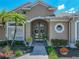 Inviting front entrance with arched entryway, double doors with decorative wreaths, and lush tropical landscaping at 2908 89Th E Ave, Parrish, FL 34219