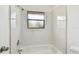 Well-lit bathroom with a shower-tub combination featuring white tile, a shower head, and a window at 2953 Yucca Ct, Palm Harbor, FL 34684
