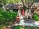 Exterior view with a well-maintained landscape, mature trees, and a red front door at 2953 Yucca Ct, Palm Harbor, FL 34684