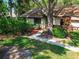 Front exterior with a large tree, shrubs, and a brick walkway leading to the red front door at 2953 Yucca Ct, Palm Harbor, FL 34684