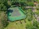 Overhead shot showcasing the tennis court near a clubhouse, complemented by manicured lawns and mature trees at 2953 Yucca Ct, Palm Harbor, FL 34684