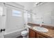 Bright bathroom with a tub, white tile surround, a mirror, and wood vanity at 3406 Pearl Dove Ln, Plant City, FL 33567