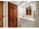 Bathroom with white vanity, decorative floral wallpaper, and wood door at 4 Belleview Blvd # 802, Belleair, FL 33756
