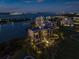 Night view of a luxurious residential building by the water, surrounded by lush landscaping and city lights at 4 Belleview Blvd # 802, Belleair, FL 33756