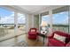 Bright living room featuring red armchairs, hardwood floors, and a balcony with stunning waterfront views at 4 Belleview Blvd # 802, Belleair, FL 33756