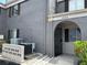 Gray two-story townhouse featuring an arched entryway, gray concrete wall, and nearby air conditioning units at 4022 Cortez Dr # A, Tampa, FL 33614