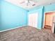 Bright blue bedroom with plush carpet, ceiling fan, and closet for storage at 4214 Canongate Ct, Spring Hill, FL 34609