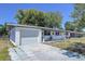 White brick exterior with an attached garage, tidy landscaping, and a well-maintained yard, exuding curb appeal at 5806 Liverpool Dr, Tampa, FL 33615