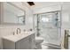 A well-maintained bathroom with a glass-enclosed shower, white wainscoting, and a gray vanity at 8330 Moulton Dr, Port Richey, FL 34668