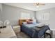 A bright bedroom with a ceiling fan, two windows, light gray walls, and a full-size bed at 8330 Moulton Dr, Port Richey, FL 34668