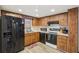 Cozy kitchen featuring wood cabinets, black appliances and laminate floors at 8330 Moulton Dr, Port Richey, FL 34668