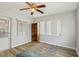 An airy room with neutral paint, laminate floors, bright windows, and a charming ceiling fan at 8330 Moulton Dr, Port Richey, FL 34668