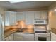 Well-equipped kitchen with white cabinetry, granite countertops, and modern appliances at 845 S Gulfview Blvd # 107, Clearwater Beach, FL 33767