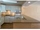 Well-lit kitchen featuring white cabinets, granite countertops, and modern appliances at 845 S Gulfview Blvd # 107, Clearwater Beach, FL 33767