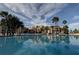 Community swimming pool surrounded by palm trees and lush landscaping and a view of the building at 845 S Gulfview Blvd # 107, Clearwater Beach, FL 33767