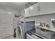 Functional laundry room featuring modern washer and dryer, ample cabinet space, and stylish tiled flooring at 8915 Hannigan Ct, Tampa, FL 33626