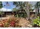 View of home showcasing colorful landscaping, mature trees, garage, and the front entrance at 919 Sandpiper S Way, St Petersburg, FL 33707