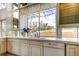 Bright kitchen showcasing white cabinets, tile countertops, and a sink with a view of the fenced backyard at 919 Sandpiper S Way, St Petersburg, FL 33707
