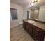 Bathroom with wood-look tile flooring, wood cabinets, large mirror, and glass-enclosed walk-in shower at 11240 Marvelwood, Brooksville, FL 34614